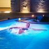 Persona rilassata in una piscina con illuminazione blu e candele attorno.