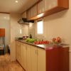 Cucina con mobile beige, stoviglie e frutta sul piano.