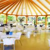 Gazebo con tavoli bianchi e sedie, circondato dal verde.