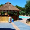Chiosco in paglia vicino a una piscina, con bidoni blu.