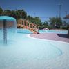 Piscina con fontana a ombrello e ponticello in legno.