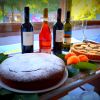 Tavolo con torte, frutta e bottiglie di vino.