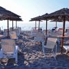 Spiaggia con sedie a sdraio e ombrelloni di paglia.