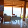 Sala da pranzo con vista mare, tavoli e sedie bianche.