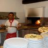 Pizzaiolo estrae pizza da forno a legna.