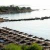 Spiaggia con ombrelloni e molo sul mare.