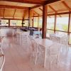 Sala luminosa con tavoli e sedie bianche, vista esterna.