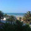 Vista sul mare con spiaggia sabbiosa e palme in primo piano.