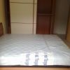 Un letto matrimoniale con materasso avvolto in plastica, davanti a un armadio.