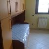 Letto singolo con materasso avvolto in plastica, inserito tra armadi e una finestra.