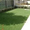 Giardino verde con prato curato, circondato da siepi e recinzioni.