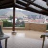 Una terrazza coperta con vista su colline e case in lontananza.