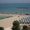 Una spiaggia affollata con lettini e ombrelloni vicino al mare calmo.