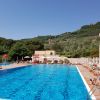 Piscina all'aperto con bagnanti, circondata da colline verdi.