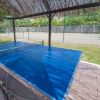 Tavolo da ping pong blu coperto da un gazebo di paglia.