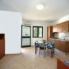 Cucina con tavolo da pranzo, credenza marrone e vista sul giardino.