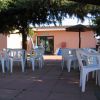 Tavoli bianchi di plastica all'aperto davanti a un edificio rosa con un'insegna.