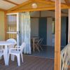 Veranda con tavolo e sedie bianche, tende aperte sul soggiorno.