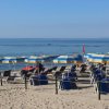 Spiaggia con file di lettini e ombrelloni giallo-blu.