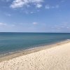 Spiaggia sabbiosa con mare calmo e cielo azzurro.