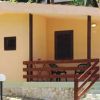 Bungalow con pareti gialle, terrazza in legno, immerso nel verde.