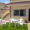 Esterno di una casa con mobili da giardino bianchi su prato.