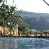 Piscina vista monti, lettini intorno, struttura in legno sopra di essa.