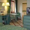 Una camera d'albergo con letti gemelli, TV, lampada e scrivania verde.