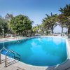 Piscina all'aperto circondata da alberi, sotto un cielo blu.
