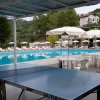 Tavolo da ping pong e piscina con lettini e ombrelloni.