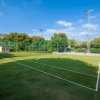 Campo da tennis all'aperto con erba e recinzione.