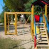 Vicino di un parco giochi con scivolo blu e strutture in legno.