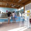 Due persone al bancone di una gelateria con interni azzurri e sedie bianche.
