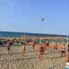 Persone giocano a beach volley sulla sabbia vicino al mare.