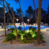 Piscina circondata da alberi e luci, fotografata al crepuscolo.