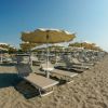 Spiaggia sabbiosa con lettini e ombrelloni.