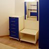 Camera moderna con mobili blu e bianchi, specchio e letto.