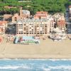 Vista aerea di una spiaggia con edifici residenziali e vegetazione sullo sfondo.
