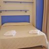 Camera con letto matrimoniale, copriletto chiaro e asciugamani piegati. Pareti e arredi in blu.