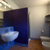 Bagno con lavabo sospeso, bidet e doccia. Pareti blu e piastrelle beige.