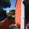 Entrata di un edificio arancio con giardino e pini sullo sfondo.