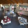 Sala da pranzo con tavoli apparecchiati, sedie bianche e finestre grandi.