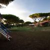 Area giochi e giardino con alberi, cielo sereno.