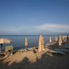 Lettini e ombrelloni chiusi su una spiaggia, vista mare sereno.