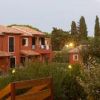 Complesso residenziale con case a due piani rosse, immerso nel verde.