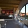 Interno di un bar moderno con ampie vetrate che offrono vista su un giardino.