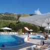Piscina con ombrelloni e persone che nuotano. Montagna sullo sfondo.