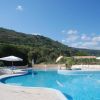 Piscina vuota con ombrelloni bianchi. Collina verde sullo sfondo.