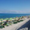 Spiaggia con ombrelloni verdi e gialli e mare blu.