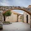 Arco in pietra tra edifici con cielo nuvoloso.